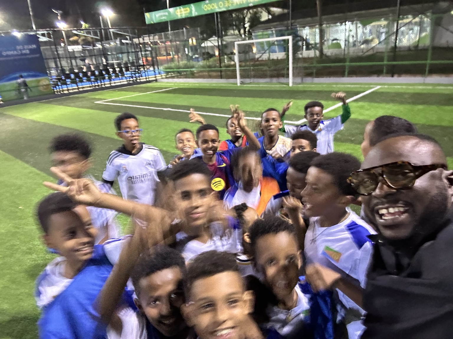 A group of young footballers and an adult smiling for a photo